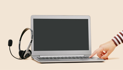 Front view of slim laptop with headset on beige. Female hand turning on. Distant learning. working...