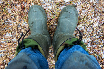 Feet in boots on the frozen ground. View from above