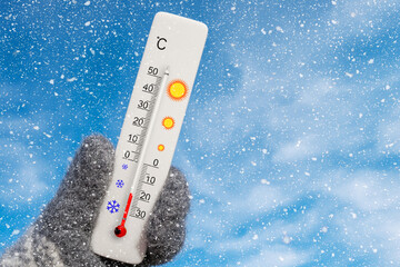 Winter holidays with snow. White celsius scale thermometer in hand. Ambient temperature minus 18 degrees celsius