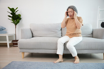 senior woman have a headache on a sofa - obrazy, fototapety, plakaty