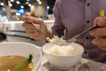 Close-up of a person holding white rice on a spoon