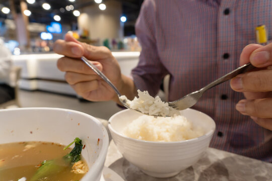 Close-up of a person holding white rice on a spoon