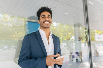 Smiling black businessman with cellphone looking away