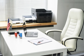 Workplace of specialist in visa center with laptop, form and stamps