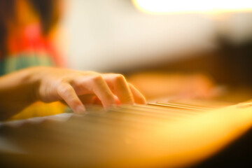 Close-up of a little student's hand playing the piano. Happy young Asian girl learning and practicing the piano. Selective focus.