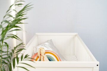 Wooden white baby crib and toy rabbit close up - obrazy, fototapety, plakaty
