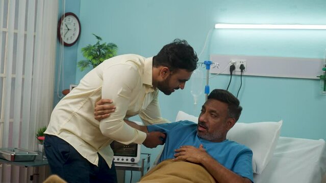 Son helping his sick senior father get up from bed while admitted at hospital ward of medical care treatment - concept of family bonding, responsibility and compassion.