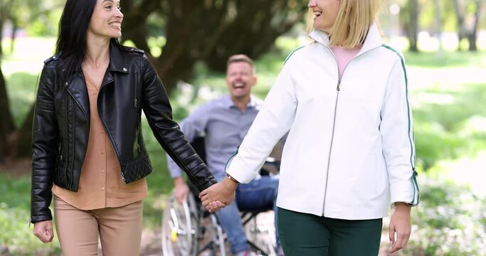Man in wheelchair screaming and trying to catch up with two women 4k movie. Difficulties in close relationships with people with disabilities concept