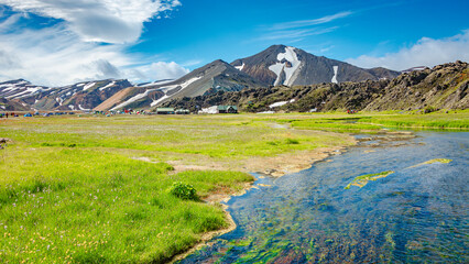 Landmannalaugar, Iceland. View at camping site and mountain hut with many tents and cars, and huge...