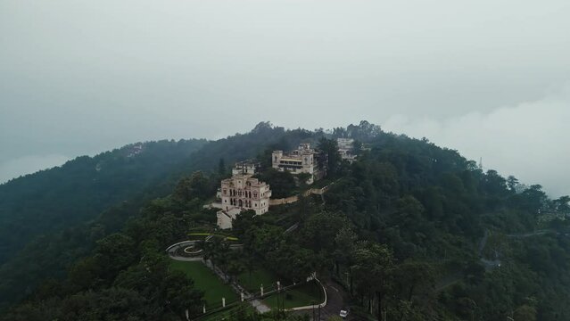 Aerial view of Narendra nagar Fort surrounded by green mountains during monsoon.Drone flying above the fort through green forest.