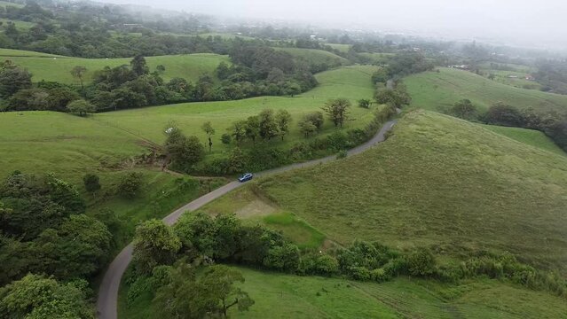 driving through mountains in modern SUV car, aerial video, drone, driving in foggy,  green mountains