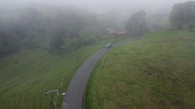 driving through mountains in modern SUV car, aerial video, drone, driving in foggy mountain with cows