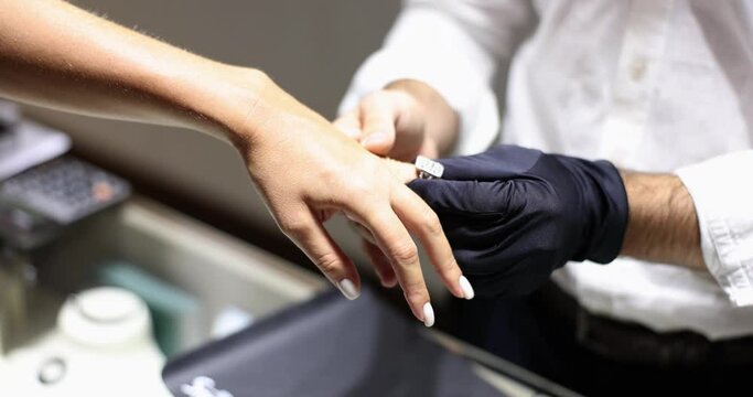 Jeweler seller in glove puts ring on woman finger. Buying and trying on expensive gold and diamond jewelry