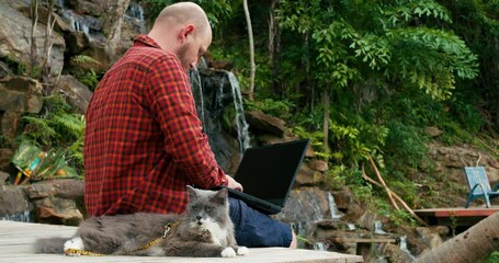 Designer near waterfall does his creative work Millennial is inspired beautiful landscape in jungle which helps him quickly complete his work Concept of working with beautiful views anywhere inworld