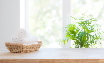 Wicker basket with white spa towels on table over bathroom window background