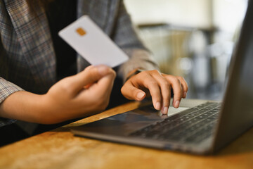 Woman hand holding credit card, paying bill with online payment via internet on laptop computer