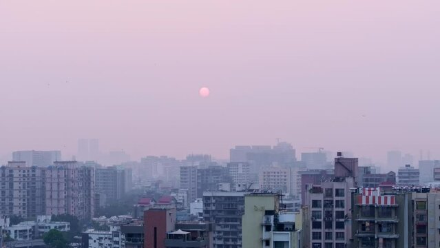Aerial view of Mumbai city with air pollution while revealing cityscape, buildings as birds cross the frame. Pedestal down reveal of Indian city with poor AQI