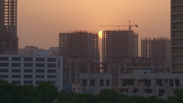 Aerial view of under construction high rise buildings with sun revealing through the structure at sunset in Noida, India. Real Estate development in India