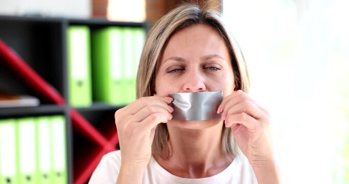 Portrait of woman sticks tape on mouth and is silent. Silence and neglect in relationships