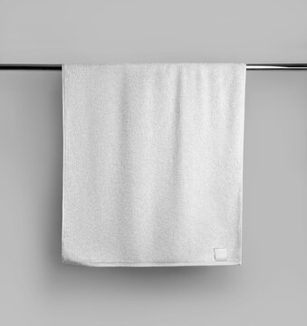 Mockup of a terry white towel with a label on a metal bar, hanging towelling for design, branding.