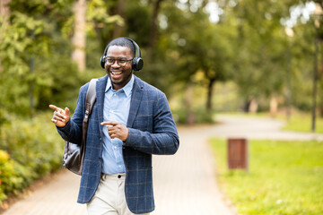 Happy man with headphones listening to music, singing and dancing while walking.