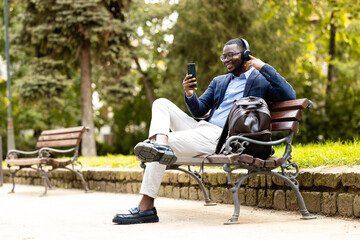 African American businessman enjoying free time, relaxing in the park on work break.