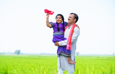 wide shot of Happy village girl kid playing with airplane toy while father holding or carrying near...