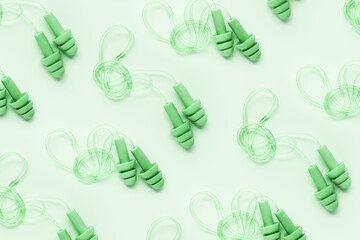 Creative flat lay pattern made green silicone earplugs for swim, sleep, rest on green background....