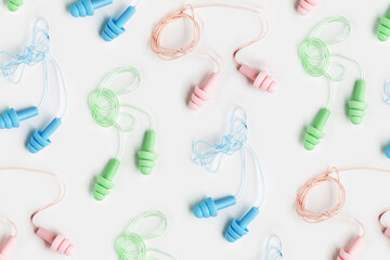 Reusable silicone colorful earplugs, for swim, sleep, rest as minimal trend pattern on white background. Soft, flexible ear plug on cord against noise, protect hear, close up, top view