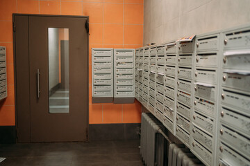 The entrance group in an apartment building with orange walls. Mailboxes are gray in color. Entrance to the house, front door in the house