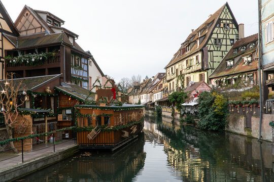 Alsace, France - Dec 16, 2023; houses and cafes with noel decorations by river or canal for Christmas in medieval town