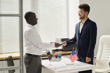 Naklejka na ściany i meble Happy African American man getting approved visa from specialist of visa center