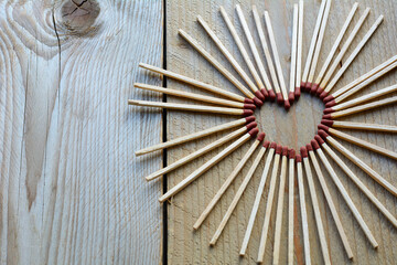 Childish heart from matches on the wooden background. Many long matches in heart form for men