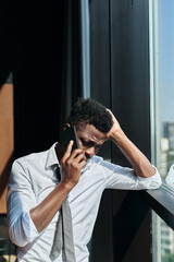 Vertical image of young man having a bad conversation on mobile phone