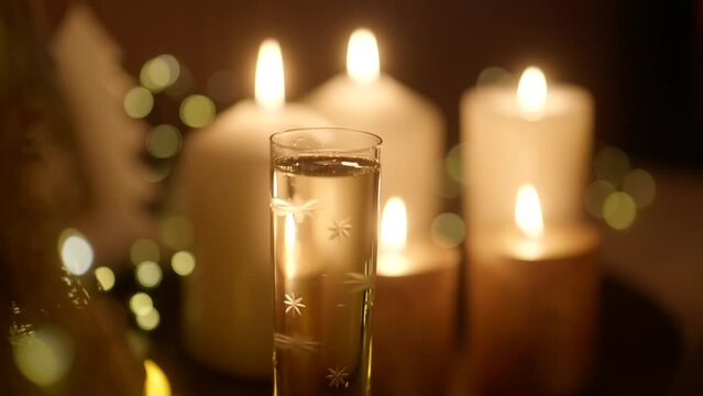 Toasting with glasses of champagne on decorated Christmas table with bokeh and warm glow near fireplace