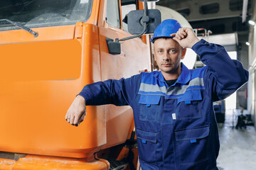 Portrait young man driver of concrete mixer truck with hard hat on cement factory