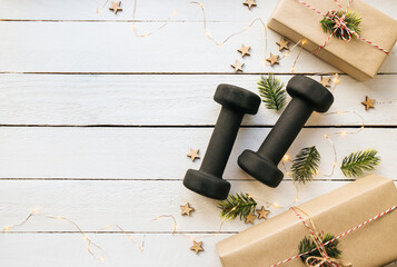 Healthy lifestyle during Christmas feasting period concept. Black dumbbells with Christmas...