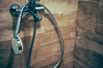 a flexible hose hanging on a bathroom tap, indoor closeup