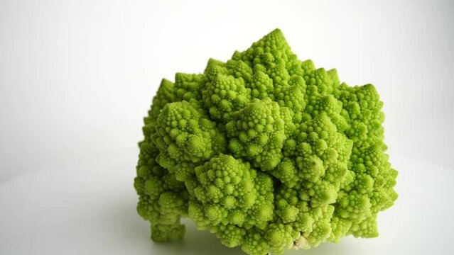 Fresh raw cauliflower romanesco rotating on white background.Green Head of Cabbage with Close up slow motion shot. Romanesco broccoli, Roman cauliflower, Broccolo Romanesco