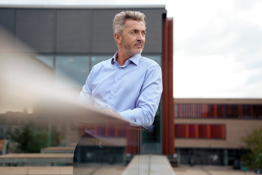 Thoughtful mature businessman standing pn balcony