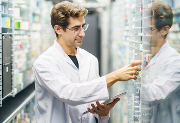 Pharmacist examining medicine stock on shelves at pharmacy