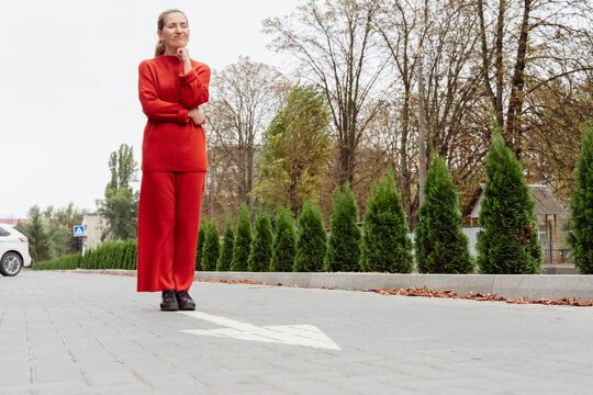 Woman with hand on chin standing near arrow sign at street