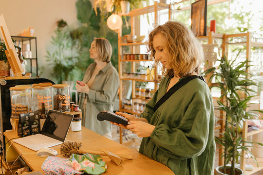 Blond woman paying through credit card reader in cafe