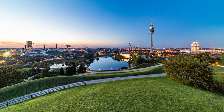 Germany, Bavaria, Munich, Panoramic view of Olympic Park with Olympic Tower, BMW Building and pond in background