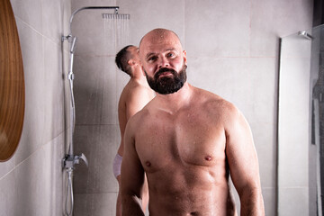 An attractive adult gay couple washes in the shower together. Love and relationship between two men.