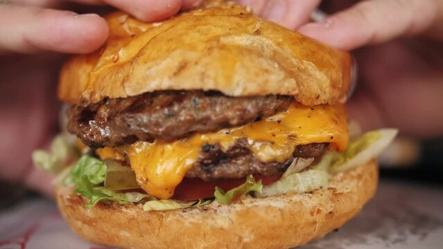 Close up of big tasty fried cheeseburger in hands.