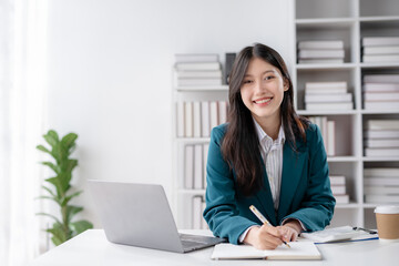 Financier working with documents at workplace. Young Asian business woman sitting working in modern office with documents and laptop computer.