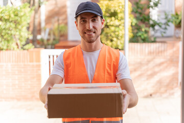 Delivery man delivering a package to the customer. Close-up of hands and cardboard box.