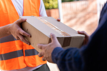 Delivery man delivering a package to the customer. Close-up of hands and cardboard box.
