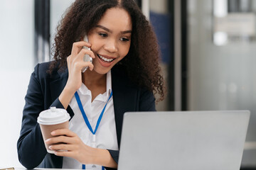 Happy african women holding phone looking at screen waving hands video call friend online in mobile chat app using laptop videochat application.